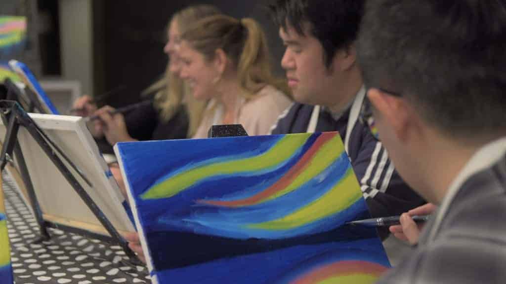 A group of people painting on small easels