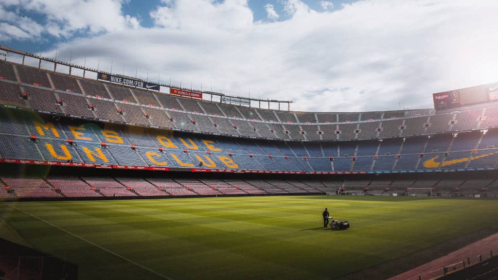 A picture of a groundskeeper maintaining the pitch at FC Barcelona's Camp Nou Stadium