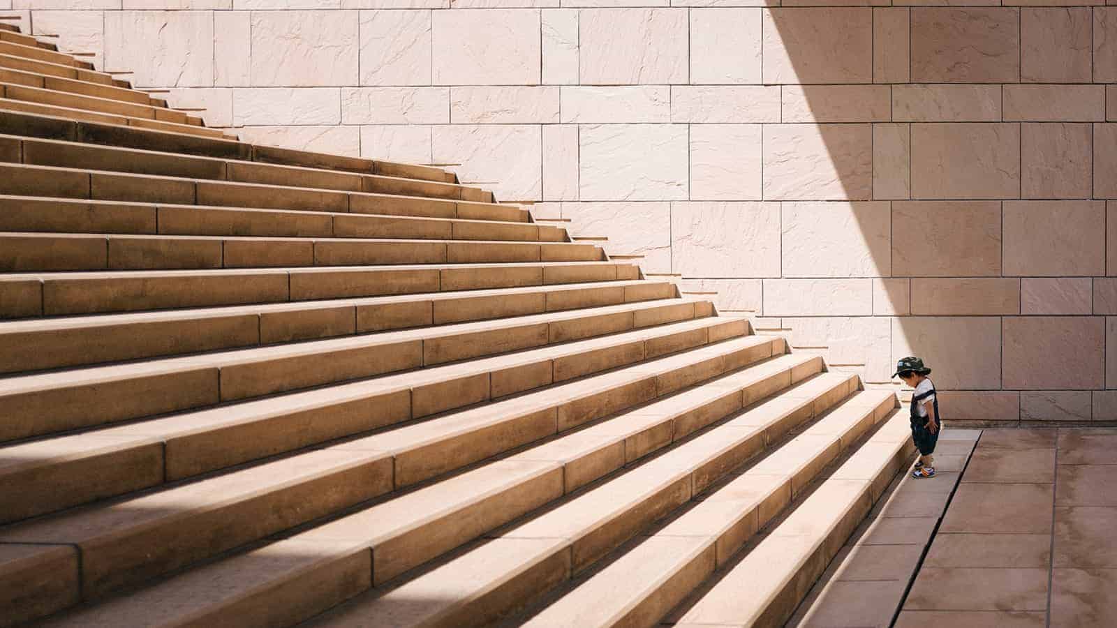 Photo of little kid ready to walk up the stair